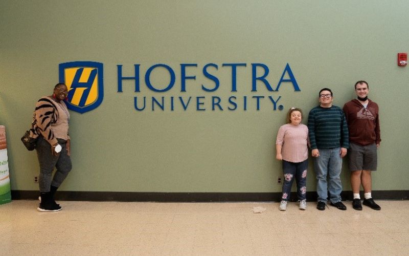 people standing in front of sign that says hofstra university